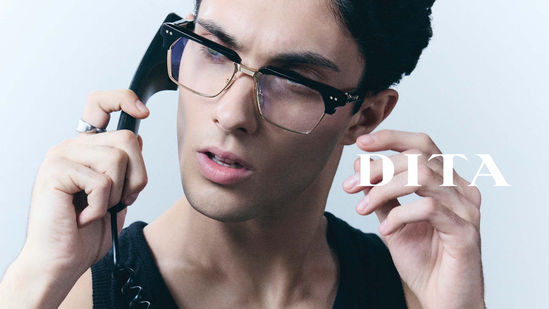 Plan rapproché d’un jeune homme, la tête légèrement inclinée, portant de grandes lunettes de soleil DITA rectangulaires avec des verres fumés qui souligne l’élégance urbaine des lunettes, désormais disponibles chez Winston Optique.