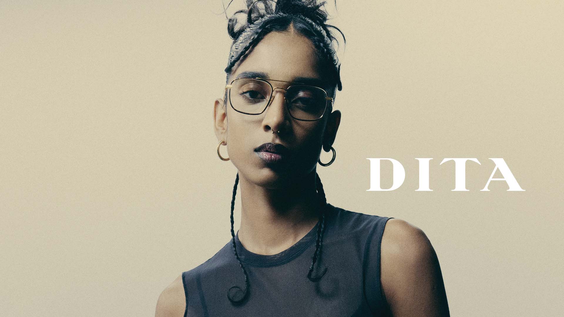 Portrait femme portant lunettes de vue DITA dorées, top noir, logo DITA à droite, désormais disponibles chez Winston Optique.