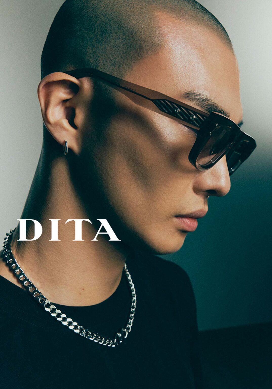 Plan rapproché d’un jeune homme, la tête légèrement inclinée, portant de grandes lunettes de soleil DITA rectangulaires avec des verres fumés qui souligne l’élégance urbaine des lunettes, désormais disponibles chez Winston Optique.